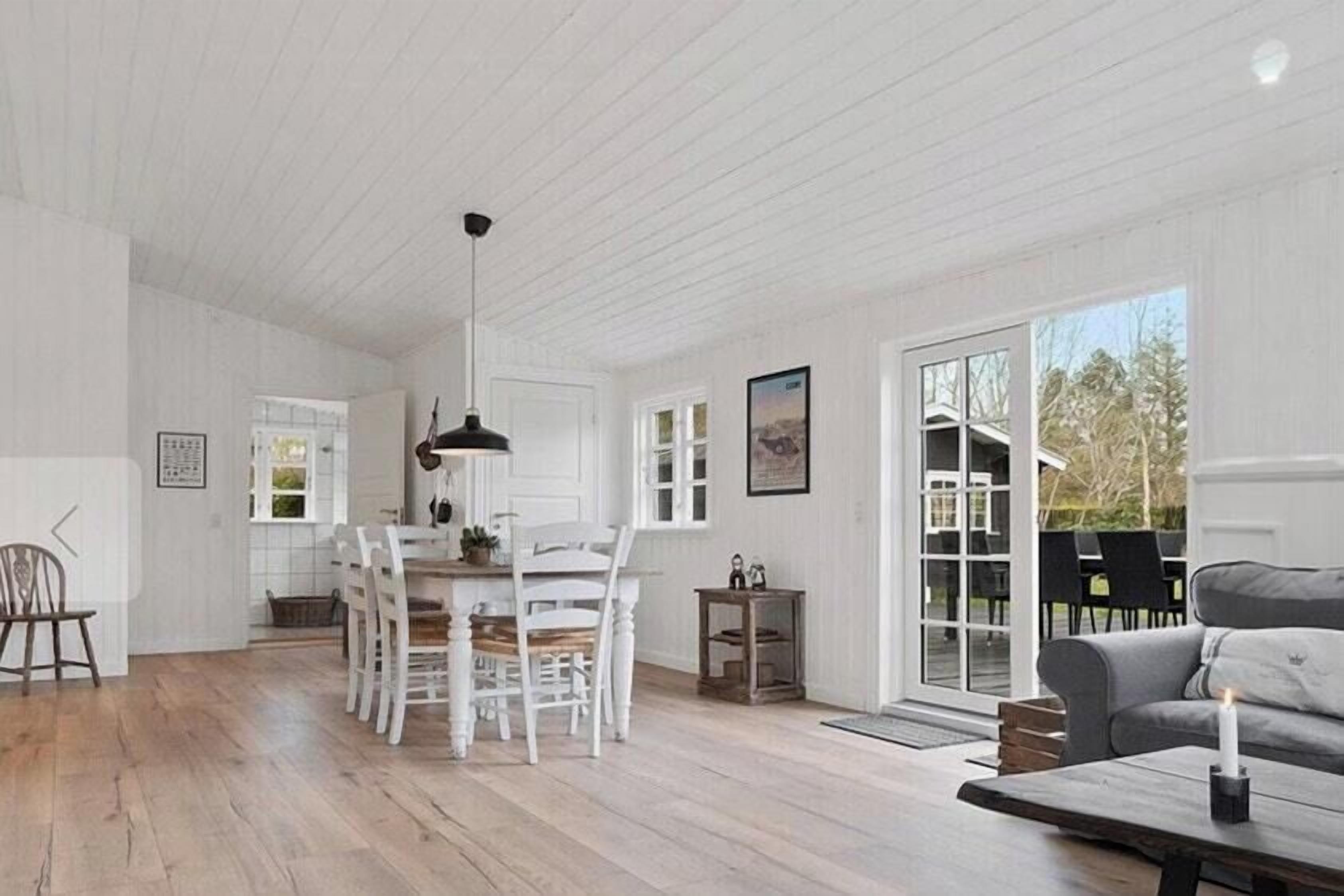 A spacious room with a dining area, a sofa, and a large window.