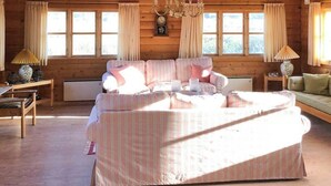Een gezellig blokhutinterieur met een groot bed, een bank, een eettafel en een kroonluchter.