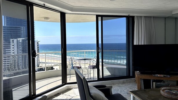 A balcony with a view of the ocean, a television, and a dining area. - Beachside Escape, VIEWS all around, steps to beach (Surfers Paradise)