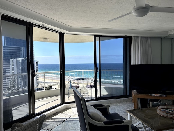 A balcony with a view of the ocean, a television, and a dining area. - Beachside Escape, VIEWS all around, steps to beach (Surfers Paradise)