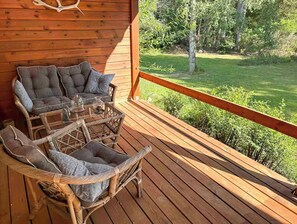 Eine Holzterrasse mit Korbmöbeln und Blick auf eine grüne Landschaft.