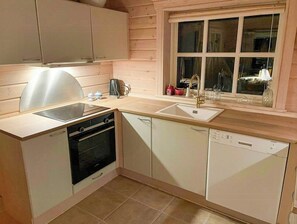 Eine kompakte Küche mit Herd, Backofen, Geschirrspüler und einem Fenster über der Spüle.