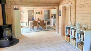 Puinen sisustus, jossa on takka, ruokailutila ja kirjahylly.