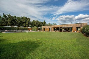 Ein modernes Gebäude mit einem großen Rasen, Außenmöbeln und einem Pool.