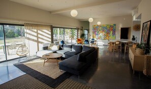 Ein modernes Wohnzimmer mit einer Eckcouch, einem Couchtisch und einem Essbereich mit Tisch und Stühlen.