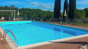 Ein Schwimmbecken mit Liegestühlen und einer Pergola.