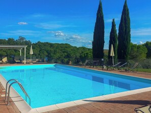 Ein Schwimmbecken mit Liegestühlen und einer Pergola.