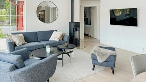 Una sala de estar moderna con un sofá modular, una mesa redonda de centro, un televisor y una chimenea.