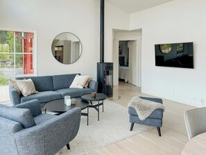 Ein modernes Wohnzimmer mit einem Ecksofa, einem runden Couchtisch, einem Fernseher und einem Kamin.