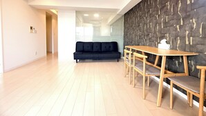 A modern living room with a sofa, wooden dining table, and chairs. - Olfea Namba South No.11 (Osaka)