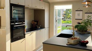 Eine moderne Küche mit Dachfenstern, einem eingebauten Backofen und einer großen Kochinsel mit Spüle.