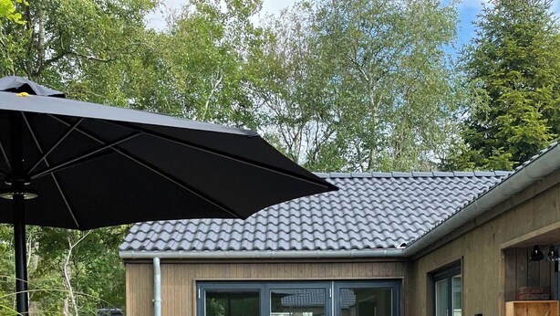 Eine Holzterrasse mit Gartenmöbeln, Blumentöpfen und einem Grill.