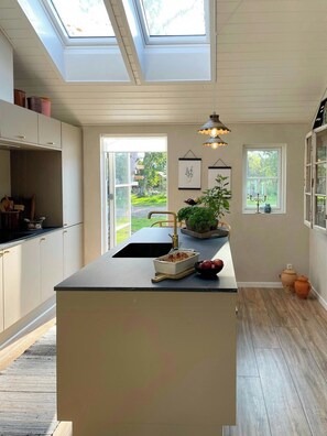 A modern kitchen with skylights, a central island, and a view of the outdoors. - Summer dreams and nature in beautiful landscape (Rødby)