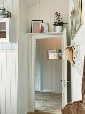 A hallway with a wooden floor, a white door, and a small window. - Summer dreams and nature in beautiful landscape (Rødby)
