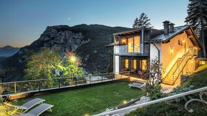 A modern two-story house with a balcony, a staircase, and a well-maintained lawn with lounge chairs. - Alpine flats in Fai della Paganella (Fai della Paganella)
