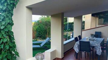 Un patio couvert avec une table et des chaises, un petit coin salon et une vue sur le jardin.