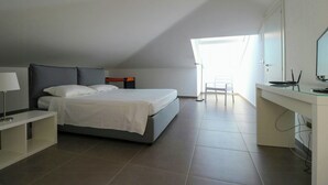 Een slaapkamer met een bed, nachtkastje, bureau, stoel en een raam.