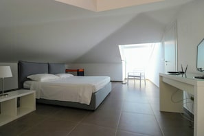 Ein Schlafzimmer mit Bett, Nachttisch, Schreibtisch, Stuhl und einem Fenster.