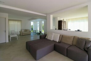 Ein modernes Wohnzimmer mit einem Ecksofa, einem weißen Couchtisch und einem Essbereich mit Tisch und Stühlen.