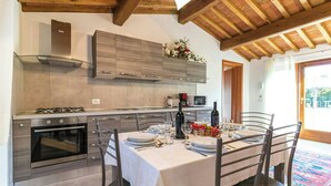 A modern kitchen with built-in appliances, a dining table set for four, and a view of the outdoors. - Orlando. Villa with private pool near Lucca (Colle di Compito)