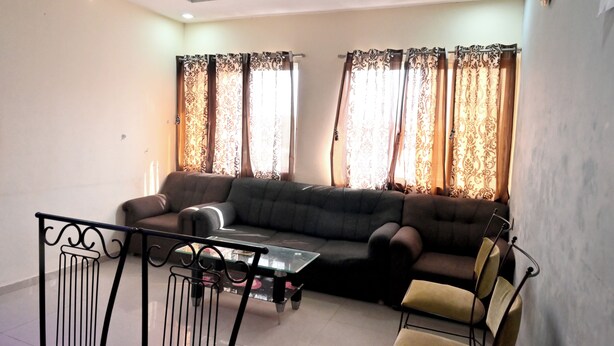 Una sala de estar con un sofá, una mesa de centro de vidrio y una mesa de comedor con sillas.