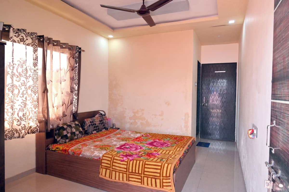 A bedroom with a bed, curtains, a ceiling fan, and a door.