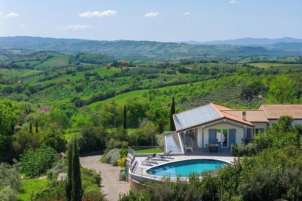 A villa with a swimming pool, surrounded by lush greenery and hills. - Exclusive villa with panoramic pool and gym (Campagnatico)