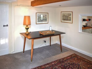 A room with a wooden table, a lamp, two framed pictures, and a patterned carpet. - 2 bedroom accommodation in Bampton (Bampton)