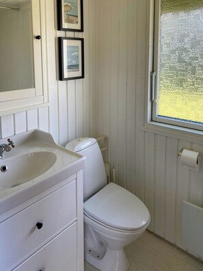 Ein Badezimmer mit einem weißen Waschbecken, einer Toilette und einem Fenster mit Milchglas.