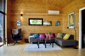 Ein Holzinterieur mit einer Couch, einem Sessel und Tischen.