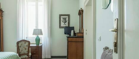 A bedroom with a bed, a chair, a dresser, a lamp, a framed picture, and a mirror.