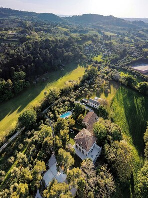 Una vista aerea di una proprietà con piscina, diversi edifici e vegetazione circostante.