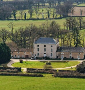 A large, multi-story building with a symmetrical facade, surrounded by a well-maintained lawn and a few trees. - French countryside house near Saint-Savin Abbey (Journet)
