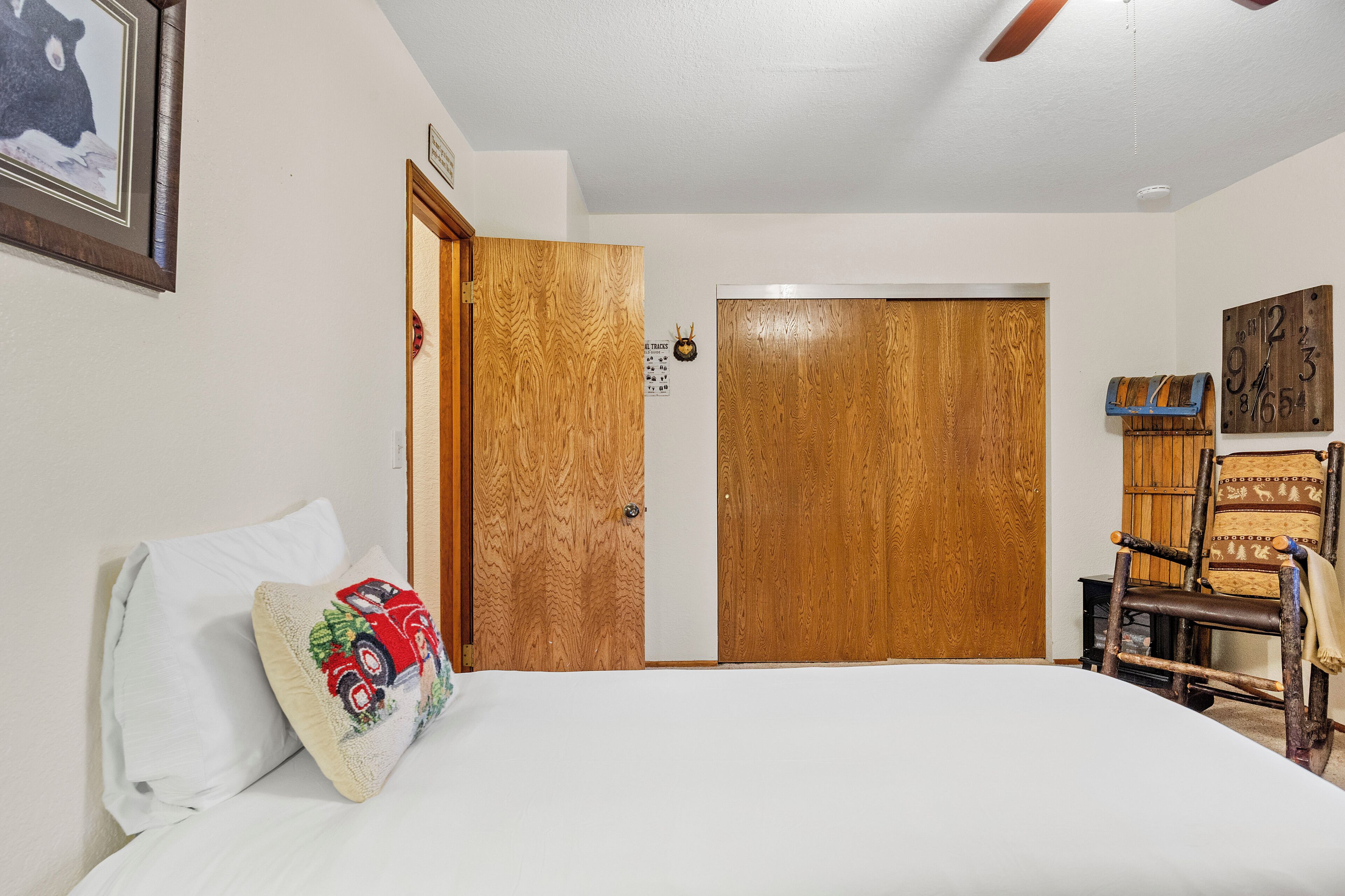 Une chambre à coucher avec un lit, une porte en bois, une chaise et une horloge murale.