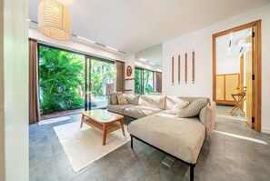 Ein modernes Wohnzimmer mit Sofa, Couchtisch und großen Fenstern mit Blick auf einen Pool.