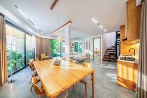Ein modernes Interieur mit einem Holzesstisch, einer Couch, einer Treppe und einer Küchenzeile.