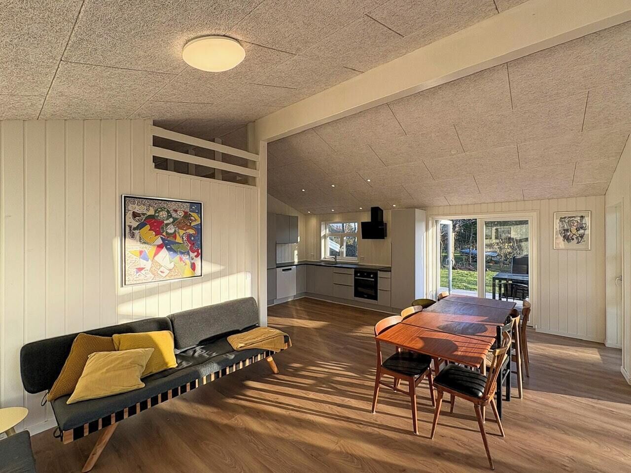 Een ruime woonkamer met een bank, eettafel en keuken op de achtergrond.