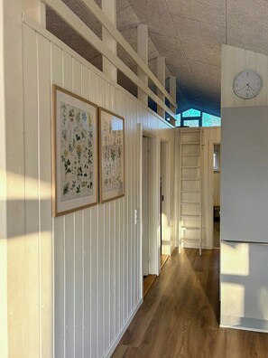 A hallway with white paneling, framed botanical prints, a wooden floor, and a clock on the wall. - Holiday home close to beach near Norsminde (Odder)
