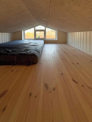 A room with a sloped ceiling, wooden flooring, a bed, and a window with a view. - Holiday home close to beach near Norsminde (Odder)