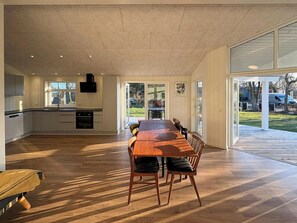 A spacious kitchen with a dining area, large windows, and a view of the outdoors. - Holiday home close to beach near Norsminde (Odder)