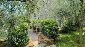 Un bâtiment en pierre doté d’un jardin, d’un mur en pierre et d’une clôture en métal.