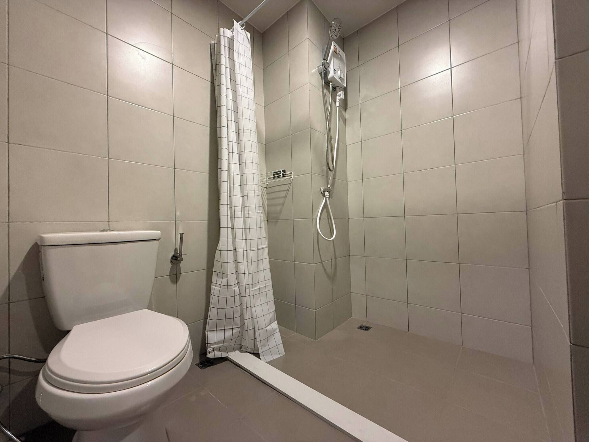 Un bagno con il water, una doccia con tenda e pareti rivestite di piastrelle.