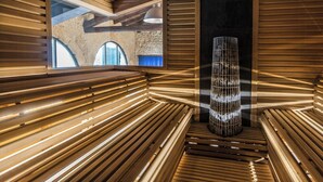 Interior moderno com ripas de madeira, luminária central e vista para uma estrutura de pedra exterior.