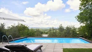 Una piscina con sillones de descanso y vistas al paisaje.
