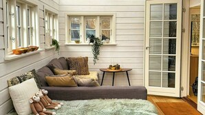 Una habitació acollidora amb un sofà, un pouf esponjós, una taula petita i una finestra amb vista.