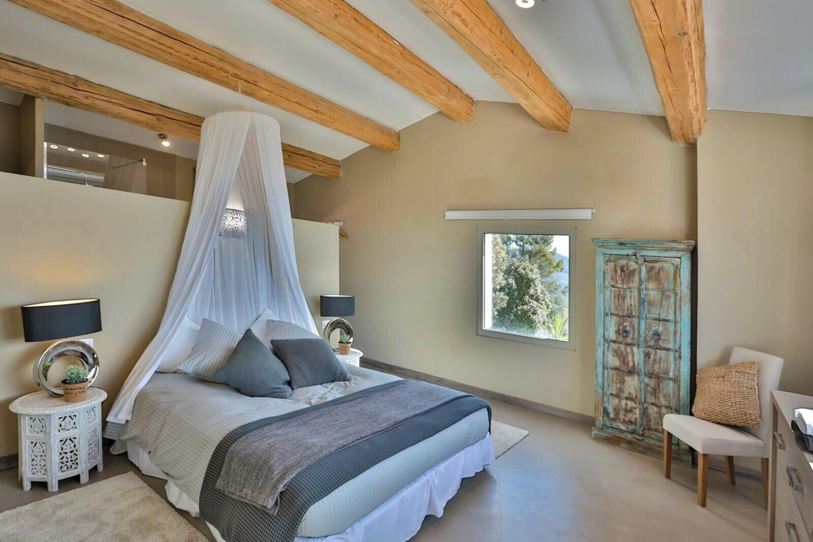 Une chambre à coucher avec un lit, des tables de chevet, une fenêtre et une chaise.