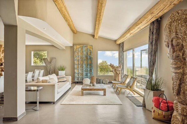 A spacious living area with a modern sofa, a coffee table, and a large window providing a view of the outdoors. - Mediterranean villa with French Riviera views (Cabris)