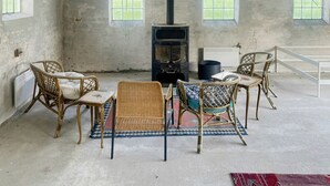Een rustieke kamer met een open haard, rieten meubels en uitzicht op groen.