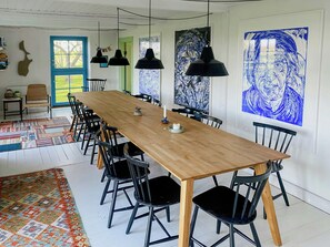 Ein langer Esstisch mit schwarzen Stühlen, einem gemusterten Teppich und Kunstwerken an den Wänden.