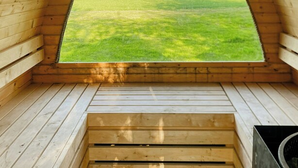 Een houten kamer met bogen en een raam dat uitkijkt over een groen veld.